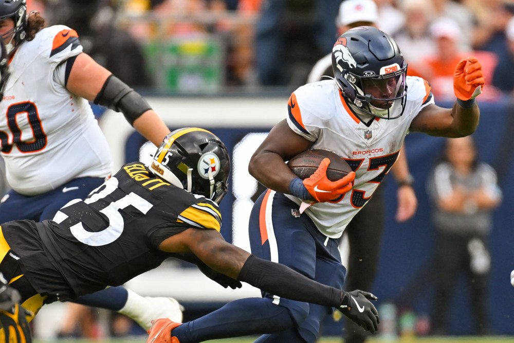 Denver running back Javonte Williams (33) runs the ball as Pittsburgh safety DeShon Elliott (25) tries to pull him down during a game between the Denver Broncos and the Pittsburgh Steelers at Empower Field at Mile High in Denver, CO on September 15, 2024.