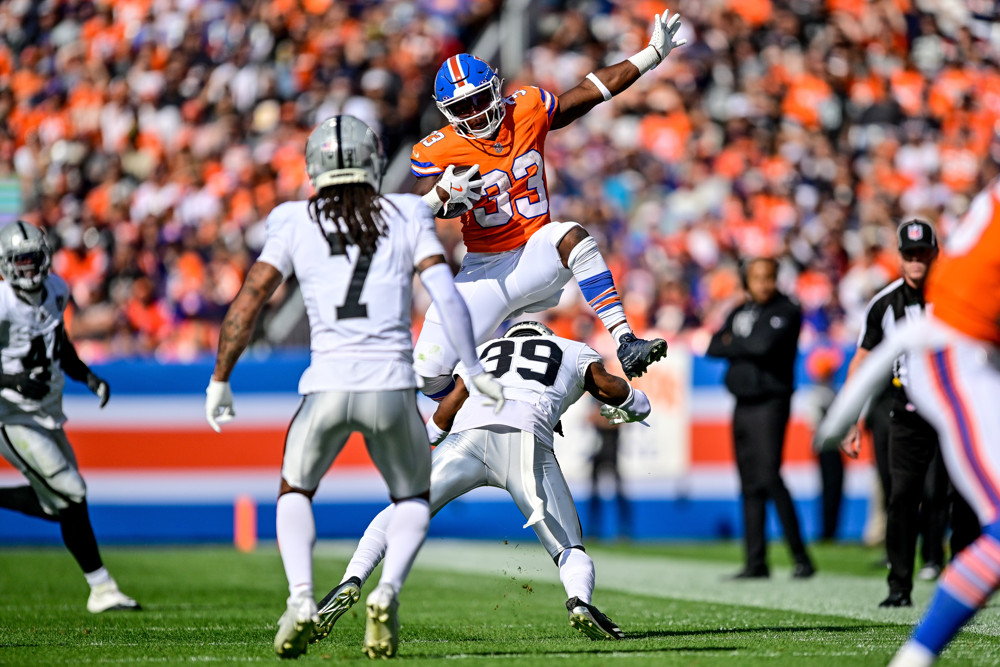 Denver Broncos running back Javonte Williams (33) leaps over Las Vegas Raiders cornerback Nate Hobbs (39) after a catch in the second quarter during a game between the Las Vegas Raiders and the Denver Broncos at Empower Field at Mile High on October 6, 2024 in Denver, Colorado. (Photo by Dustin