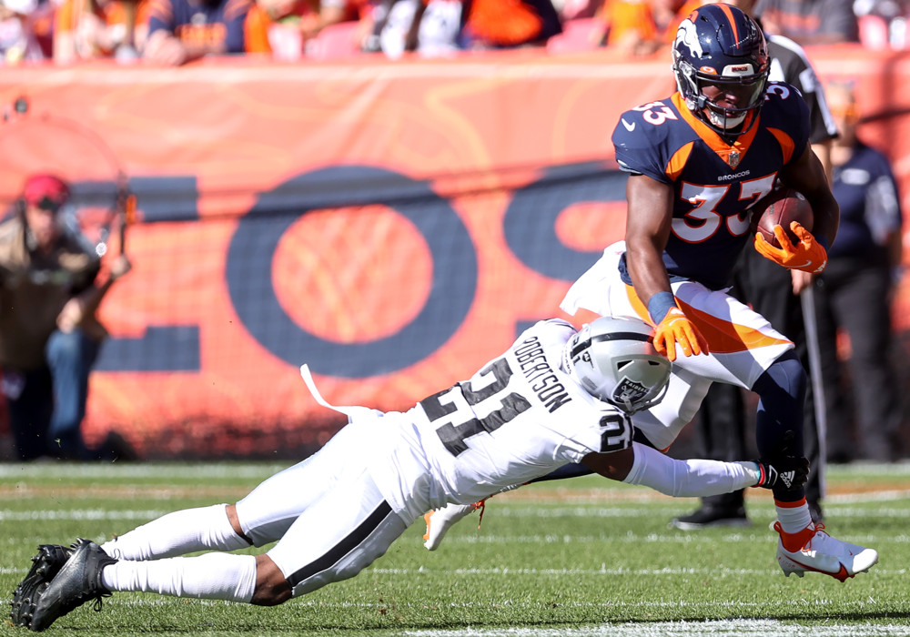 Denver Broncos running back Javonte Williams (33) tries to avoid Las Vegas Raiders cornerback Amik Robertson (21) during a NFL game between the Las Vegas Raiders and the Denver Broncos on October 17, 2021 at Empower Field at Mile High in Denver, CO. 