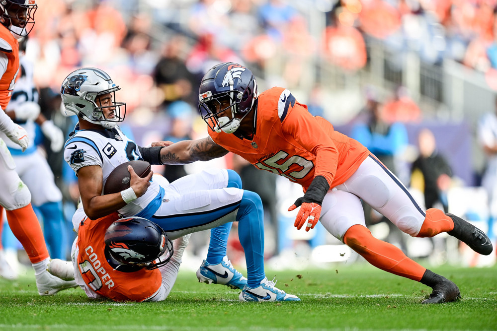 Carolina Panthers quarterback Bryce Young (9) is sacked by Denver Broncos linebacker Jonathon Cooper (0) and linebacker Nik Bonitto (15) during a game between the Carolina Panthers and the Denver Broncos at Empower Field at Mile High on October 27, 2024 in Denver, Colorado.