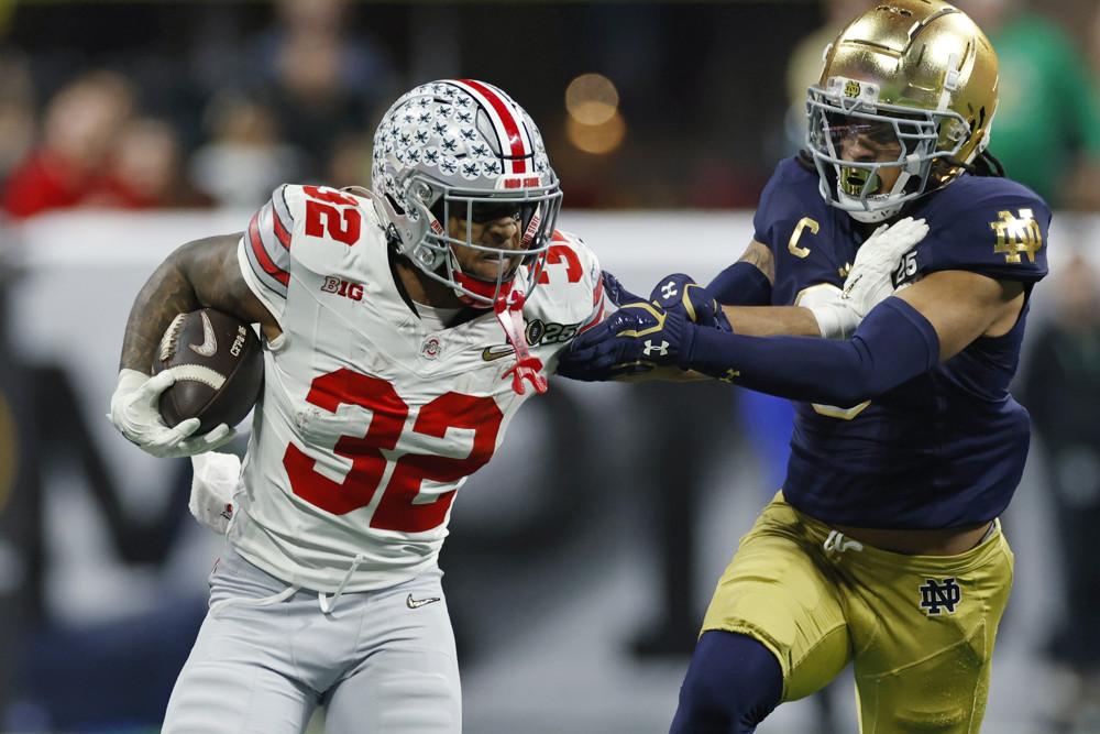 Ohio State Buckeyes running back TreVeyon Henderson (32) runs with the ball while pursued by Notre Dame Fighting Irish safety Xavier Watts (0) during the Ohio State Buckeyes versus Notre Dame Fighting Irish College Football Playoff National Championship game on January 20, 2025, at Mercedes-Benz Stadium in Atlanta, GA. 