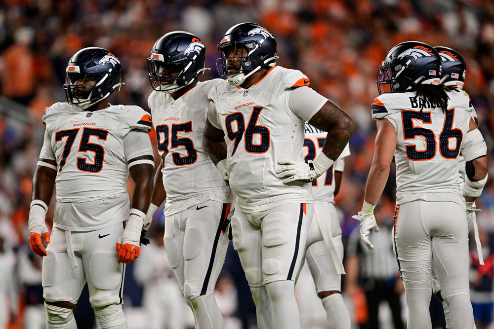 Denver Broncos defensive players including defensive end Eyioma Uwazurike (96), defensive end Sai'vion Jones (95), and defensive tackle Kristian Williams (75) look on during a preseason game between the Arizona Cardinals and the Denver Broncos at Empower Field at Mile High on August 16, 2025 in Denver, Colorado.